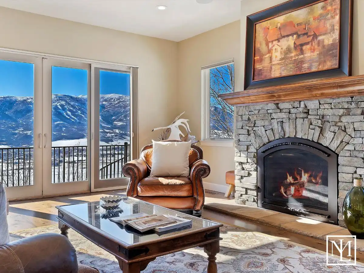 Stone fireplace in the great room with snowy mountains seen through large windows at 5932 E Big Horn Pkwy