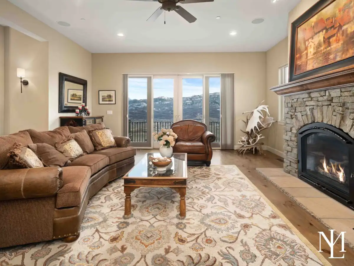 Rustic living room with stone fireplace, a couch, glass coffee table, and sliding doors out to balcony