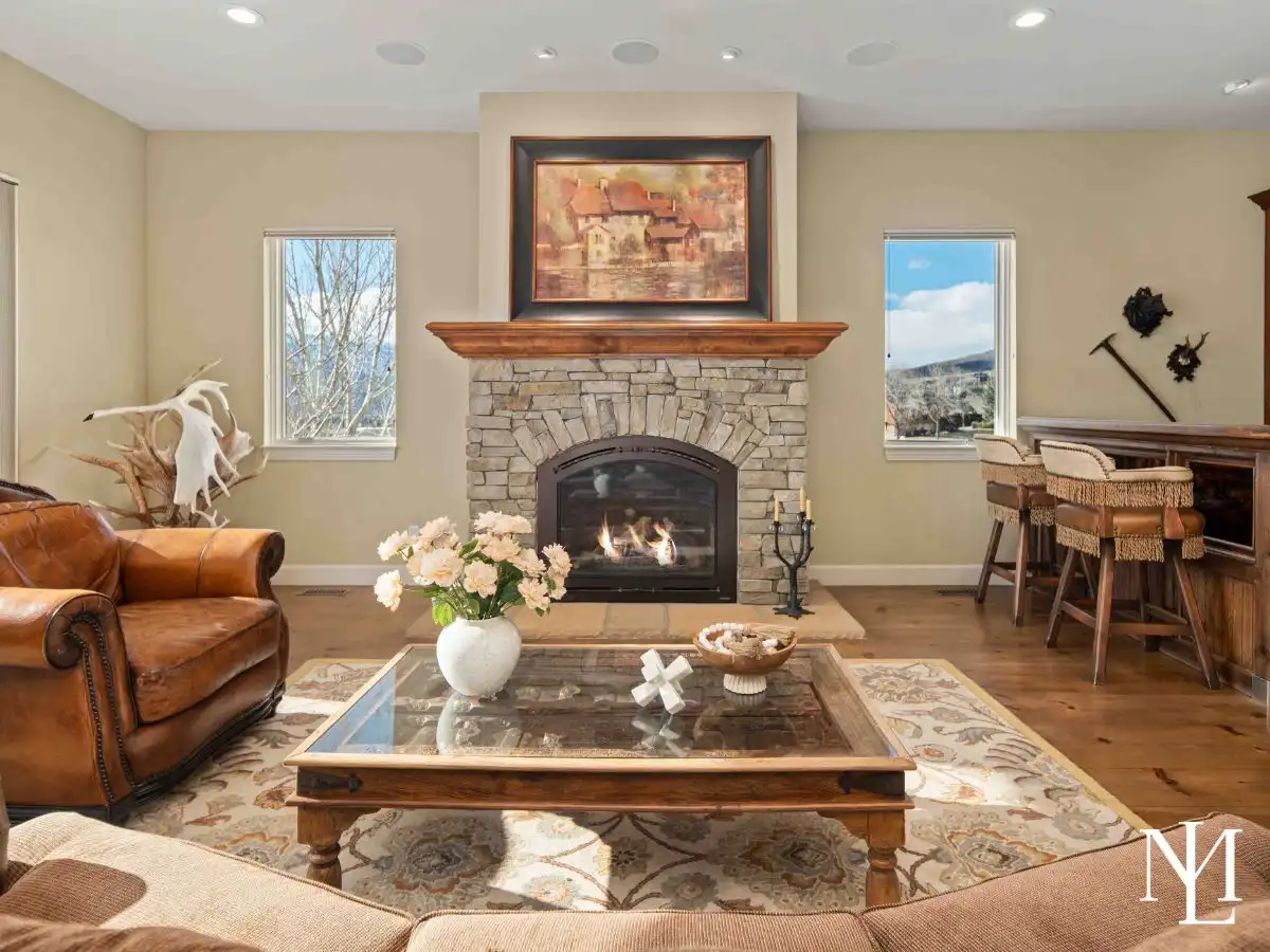 Living room with a cozy fire in the stone fireplace, to the side a bar with stools