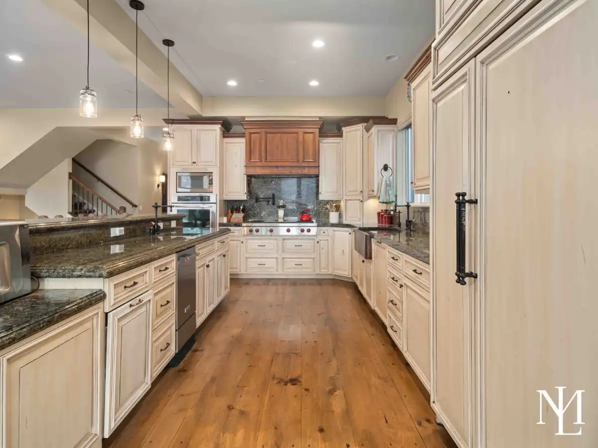 Kitchen with custom-painted cabinets, granite counters, wolf range, fridge panels, and instant hot water stations