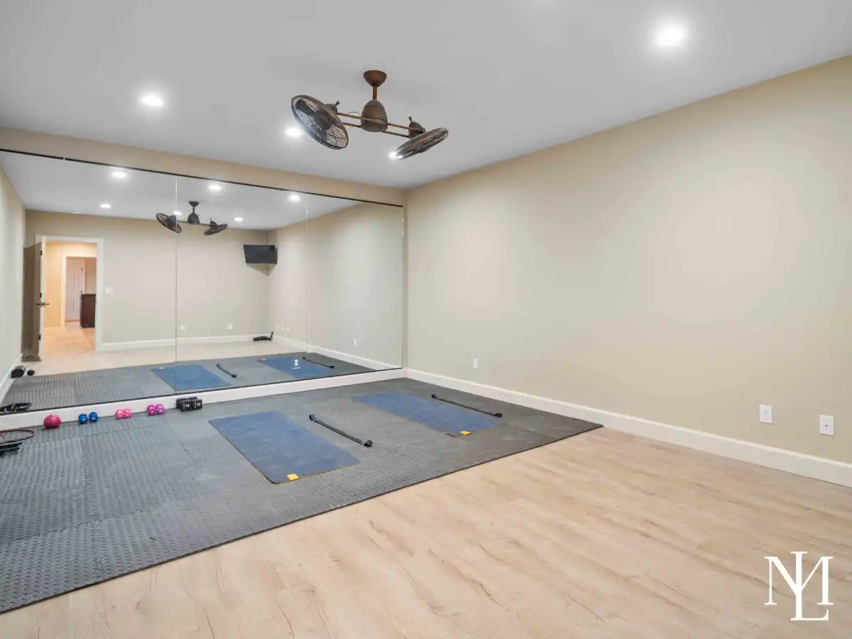 Home gym room with wall-to-wall mirror, mats, and weights