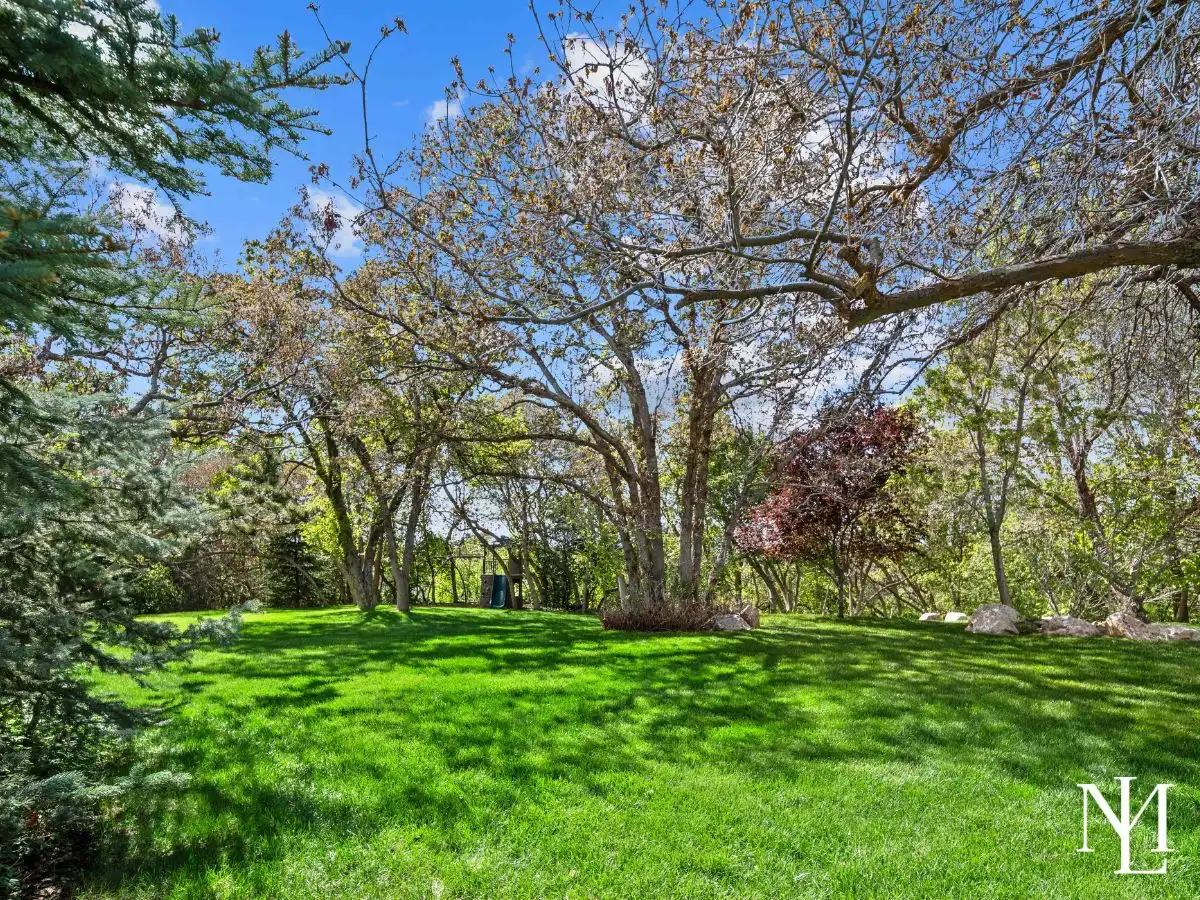Private backyard lawn surrounded by mature trees, natural shade, and a peaceful wooded setting in the Ogden foothills.