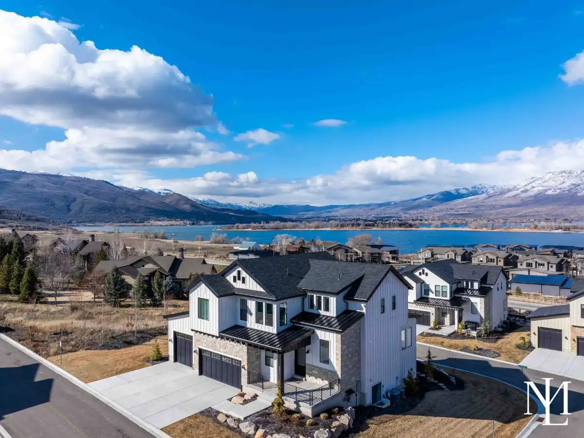 Aerial view of luxury home surrounded by other mountain homes, Pineview Reservoir, and mountain ranges.