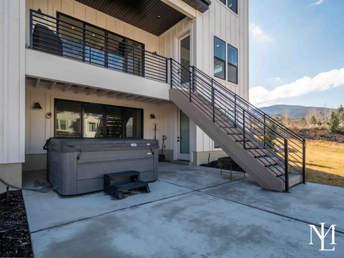 Farmhouse exterior with hot tub and stairs that lead to upper balcony