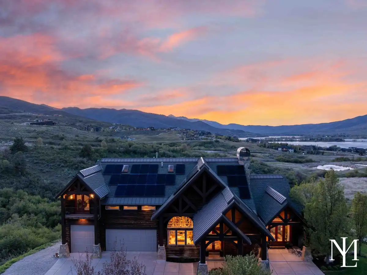 Twilight exterior of luxury mountain home in Huntsville, Utah with dramatic rooflines, solar panels, and panoramic Pineview Reservoir views.