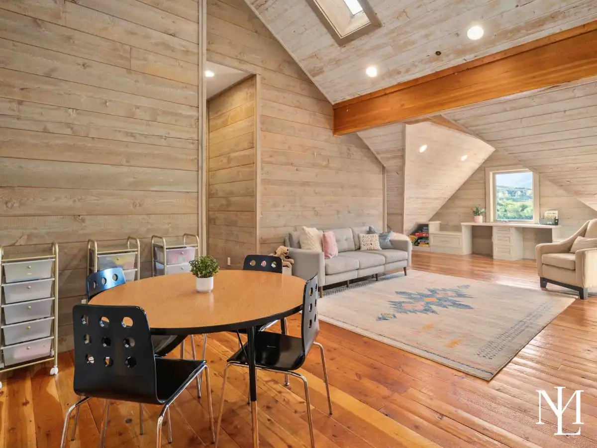 Upper-level loft with vaulted wood ceilings, sitting area, workspace, and natural light in spacious Huntsville, Utah home.