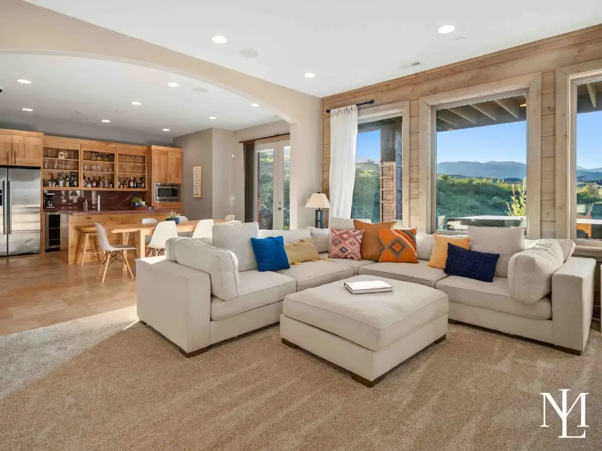 Lower-level lounge with large sectional, built-in bar, and mountain views in expansive Huntsville, Utah retreat.