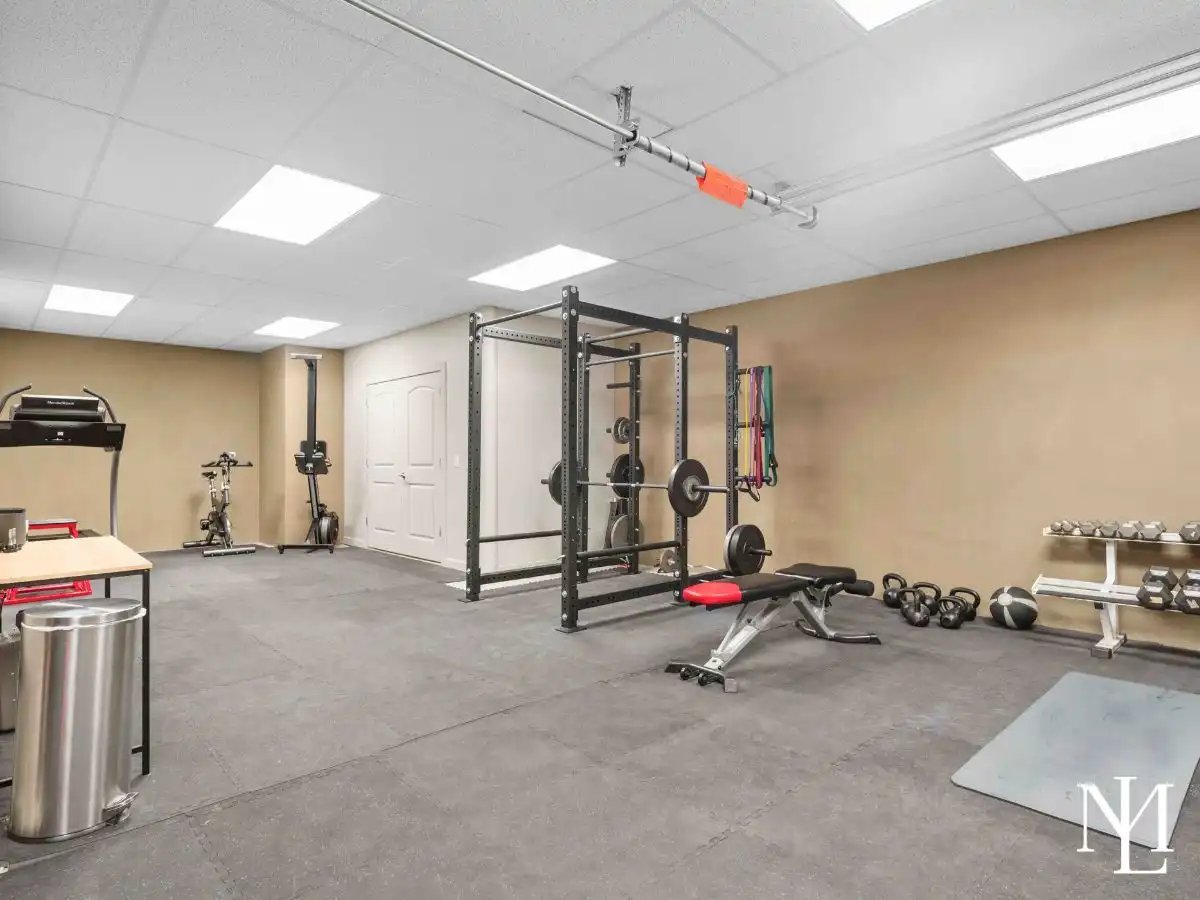 Home fitness room with weight rack, cardio equipment, and dedicated workout space in lower level of mountain estate.