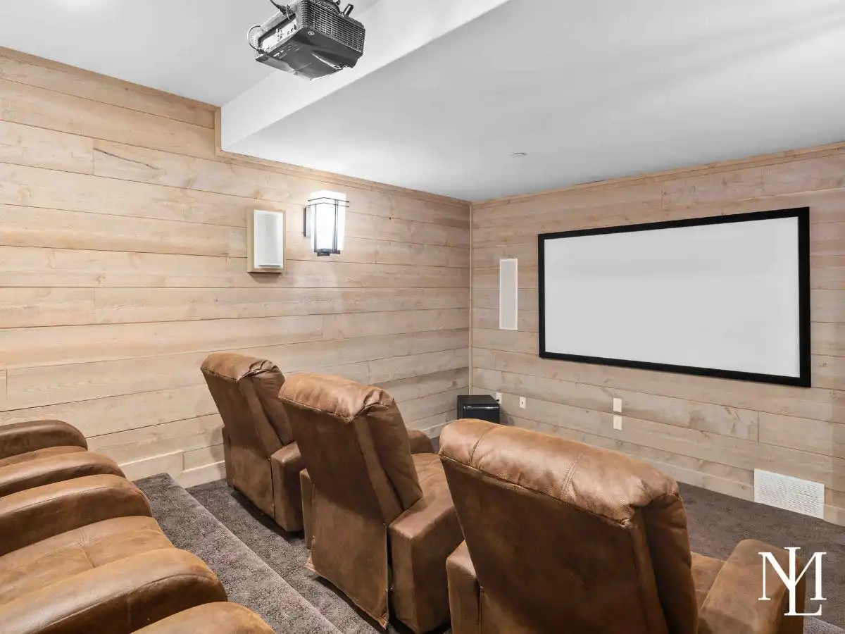 Private theater room with plush recliner seating and large projection screen in lower level of luxury Huntsville estate.
