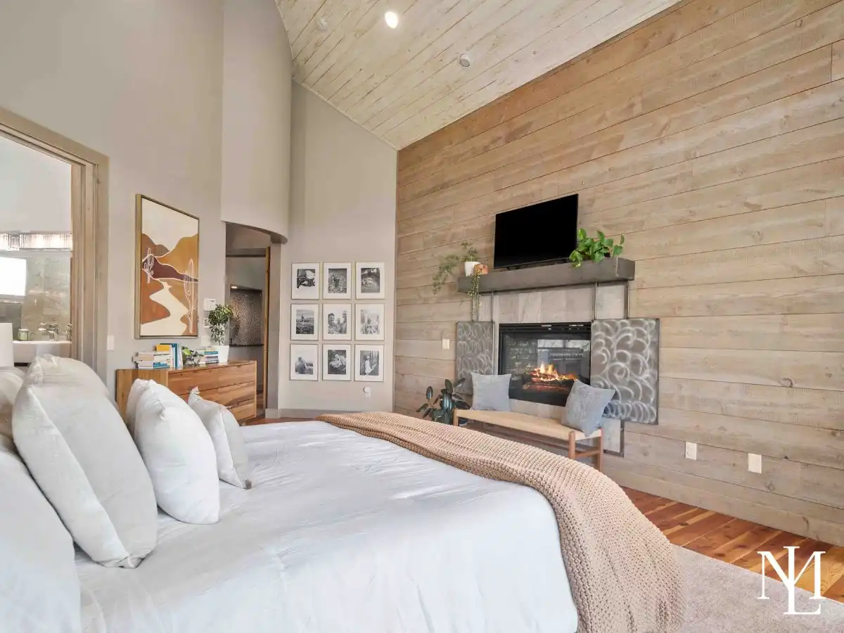 Spacious primary suite with vaulted wood ceiling, fireplace, and serene mountain-modern finishes in Huntsville luxury home.