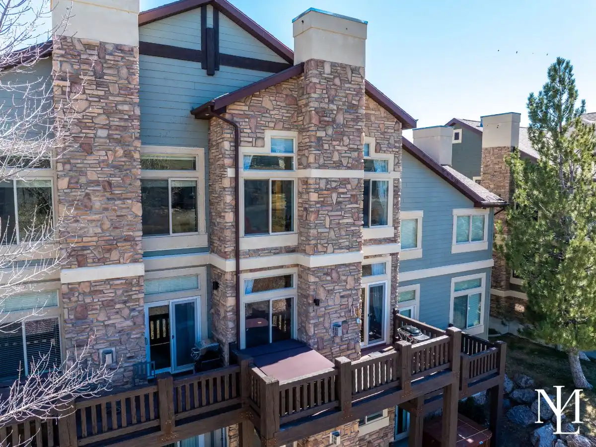 Rear exterior of Lakeside Village townhome with multiple decks and stone-and-siding mountain architecture.