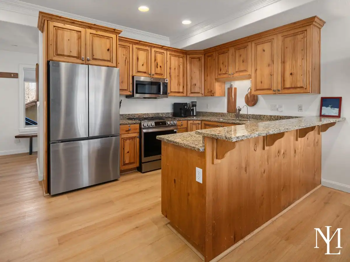 Kitchen with knotty wood cabinetry, granite countertops, stainless steel appliances, and breakfast bar.