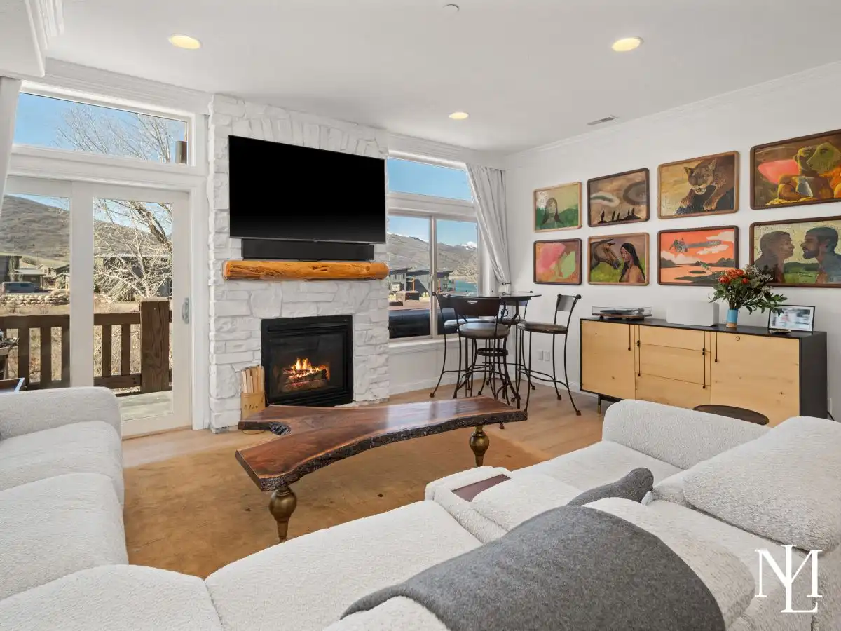 Living room with stone fireplace, large windows, deck access, and Pineview Reservoir views.
