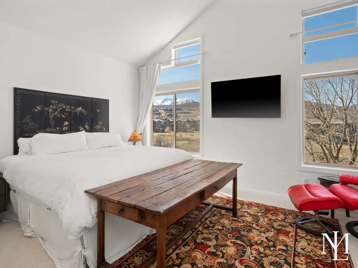 Primary bedroom with vaulted ceilings, large windows, and mountain views in Lakeside Village.