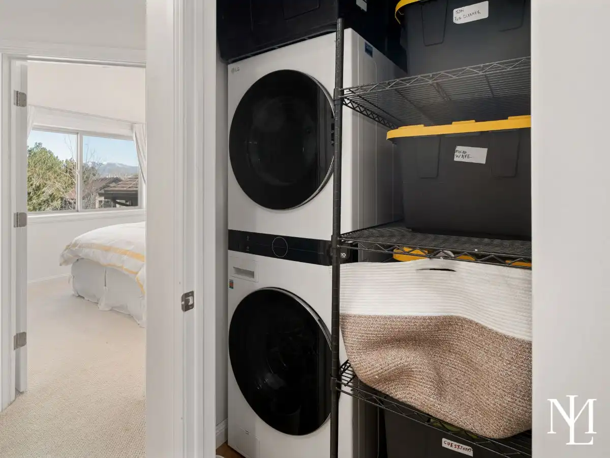 Laundry closet with stacked washer and dryer and built-in storage shelving.