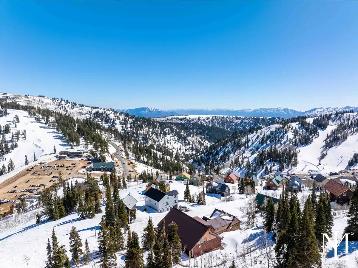 Aerial view of a snowy ski village and canyon with mountain ridgelines near Eden, Utah.