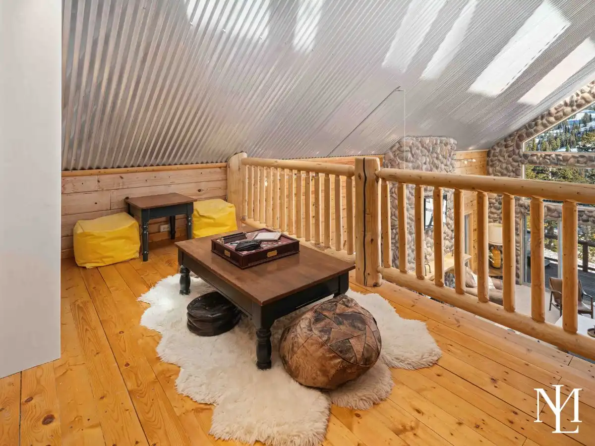 Loft lounge with wood floors, cozy seating, and corrugated metal ceiling overlooking the great room.