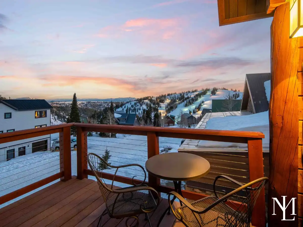 Deck bistro seating with sunset views over a snowy mountain neighborhood and ski slopes in Eden, Utah.