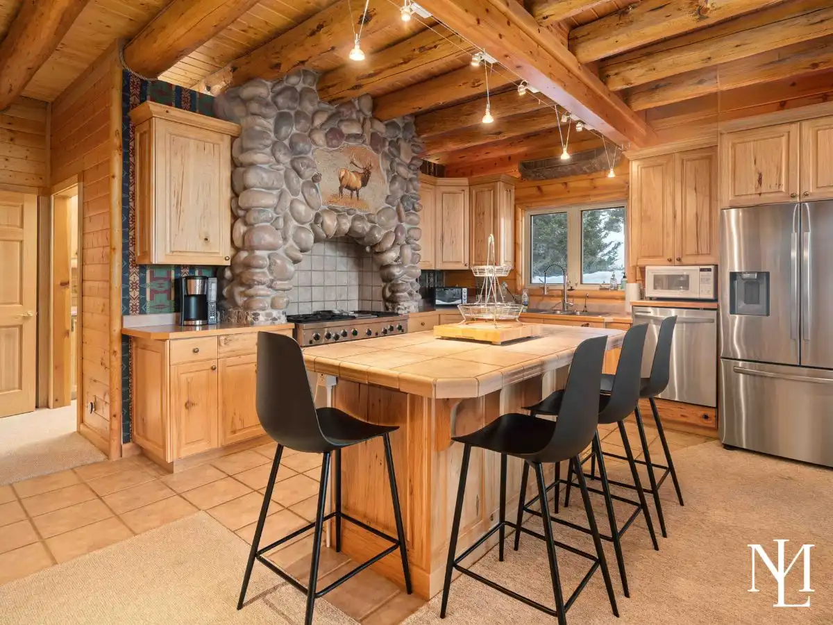 Rustic kitchen with stone range hood, large island, bar seating, and stainless appliances.