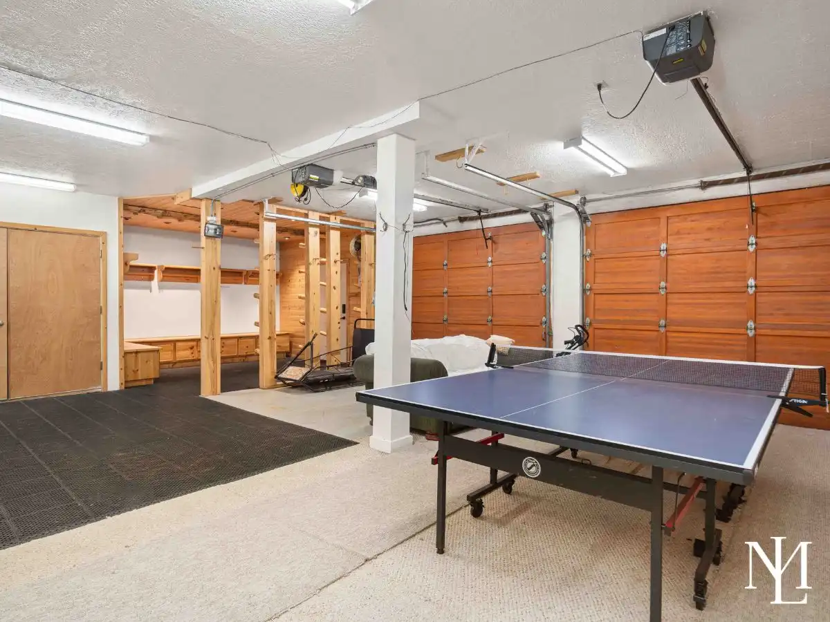 Game room with ping pong table and oversized garage doors, ideal for gear storage in an Eden, Utah cabin.