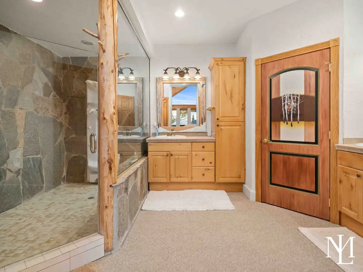 Bathroom with glass walk-in stone shower and wood vanity with granite countertop.