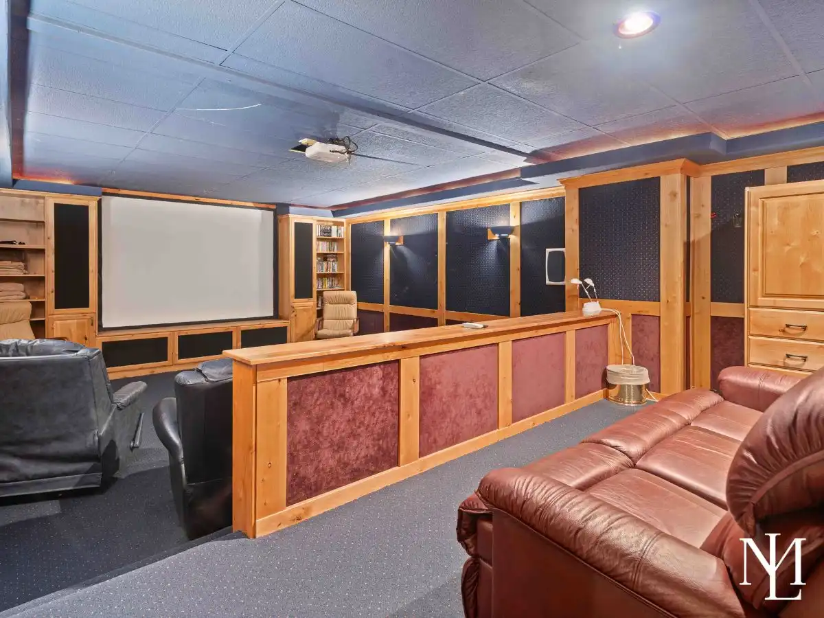 Private theater room with projector screen, built-in shelving, and comfortable seating.