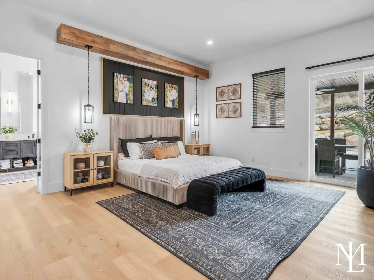 Spacious primary bedroom with wood beam detail, patio access, and neutral finishes.