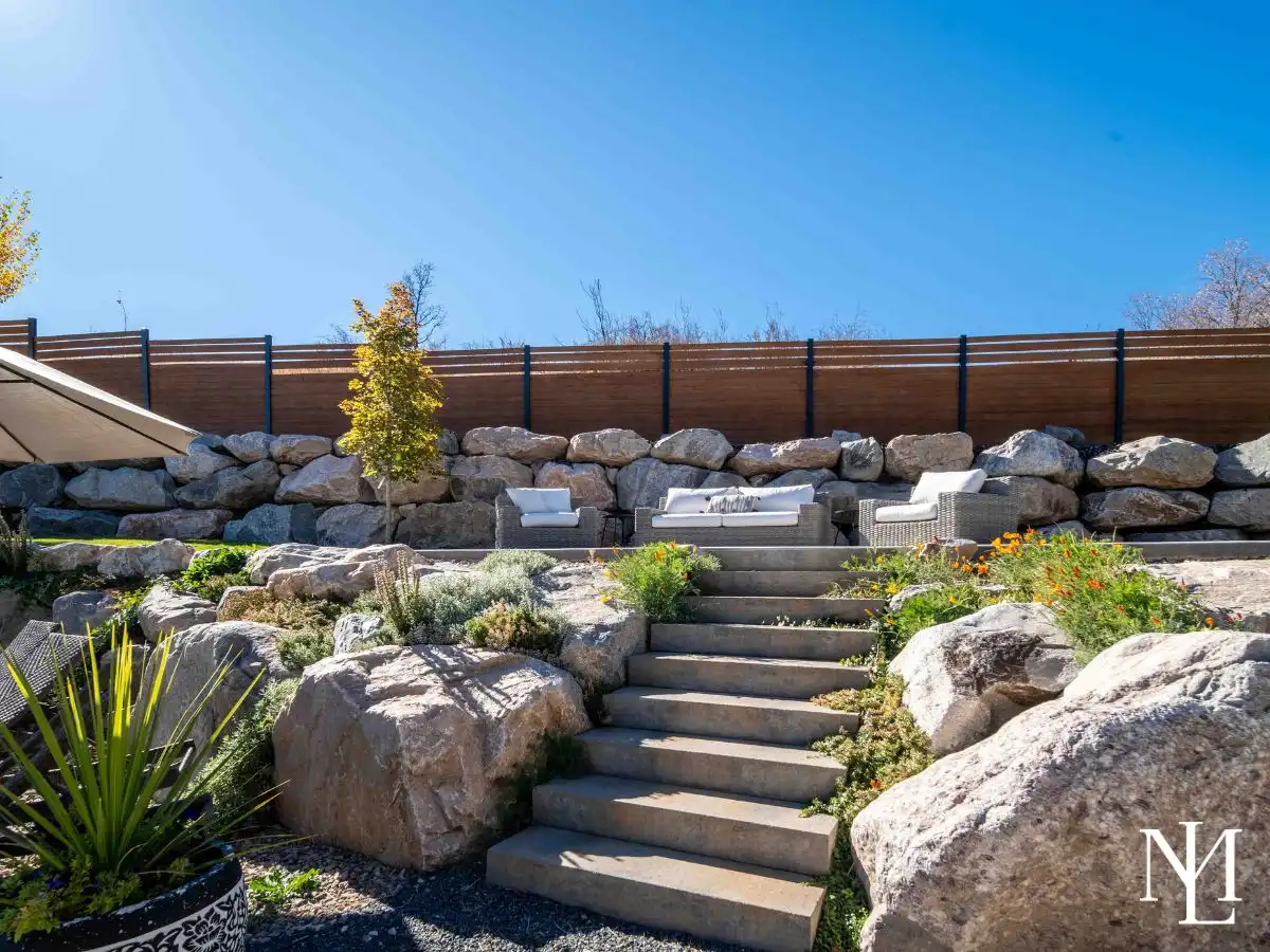 Terraced backyard landscaping with stone retaining walls, garden beds, and outdoor seating area.