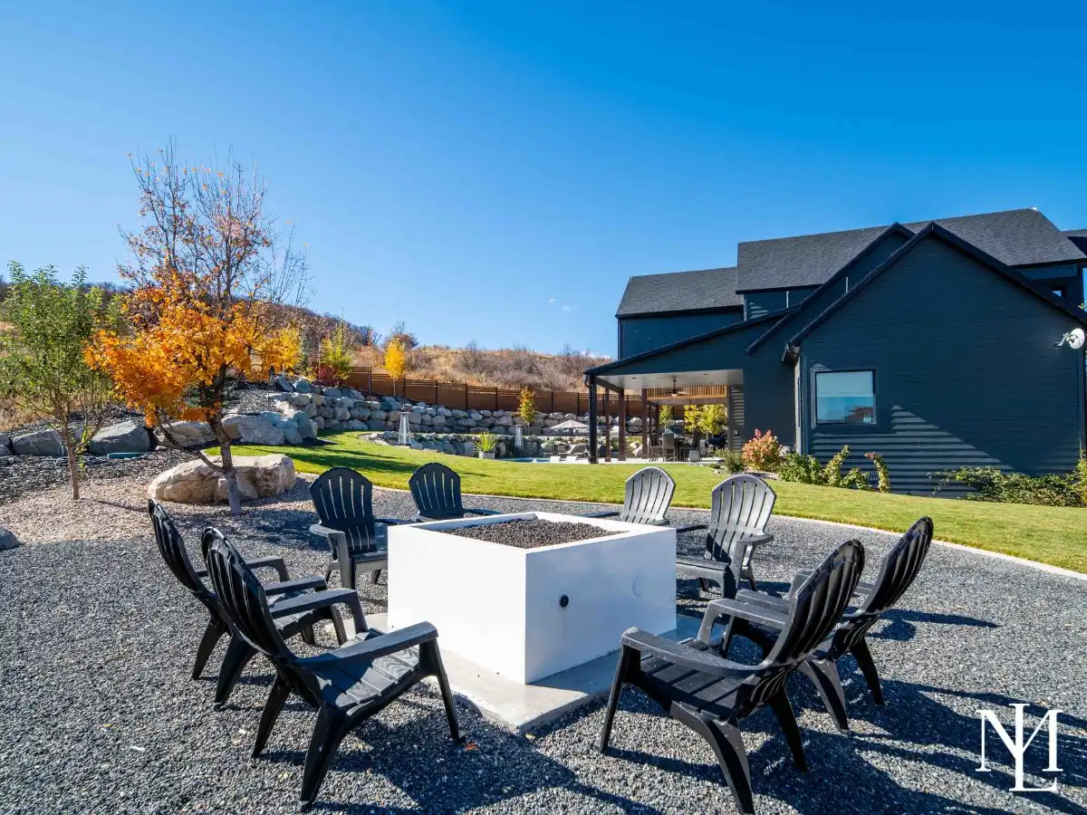 Backyard fire pit area with Adirondack chairs, lawn, and mountain setting.