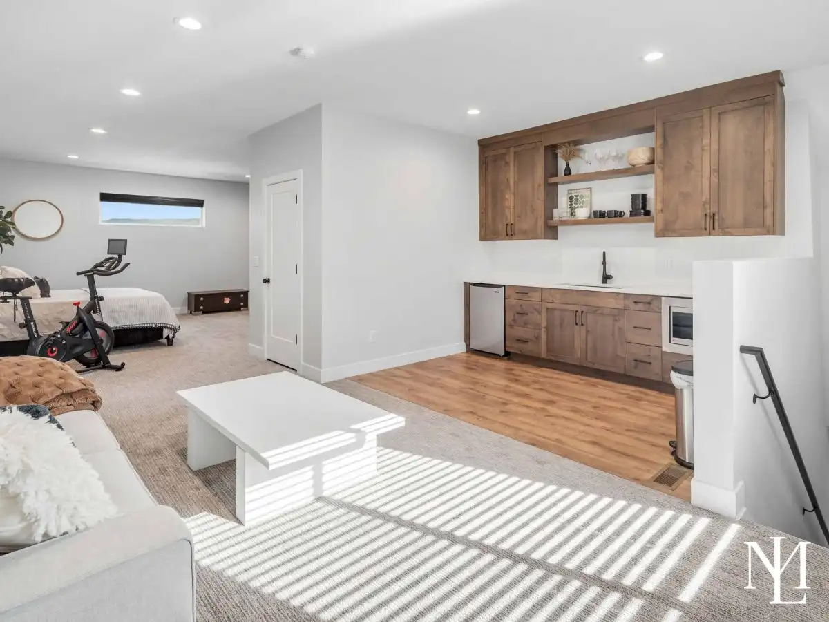 Lower-level living space with kitchenette, open lounge area, and carpeted floors.