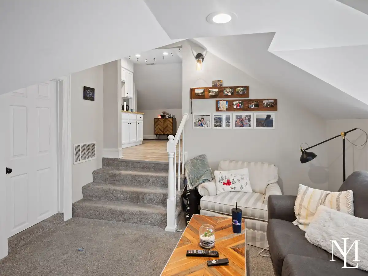 Lower-level living area in triplex home with carpeted stairs, sitting area, built-in cabinetry, and flexible living space