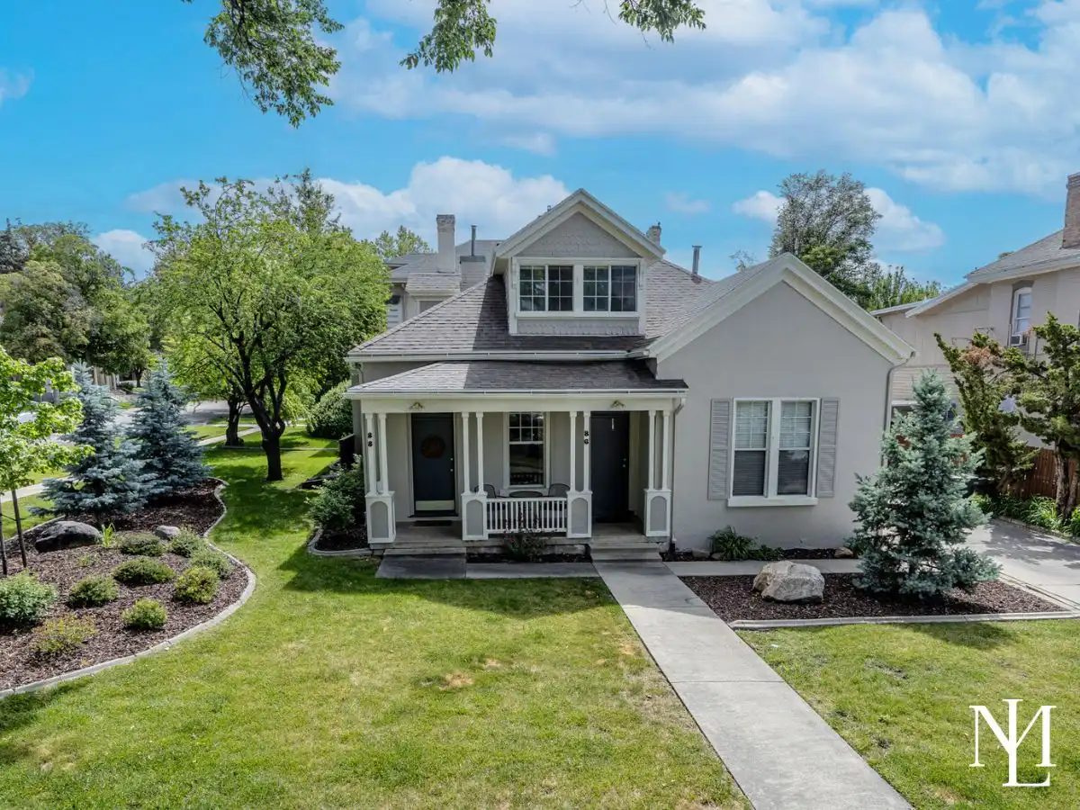 Front exterior of home with dormer window, covered porch, landscaped yard, and mature trees in the Avenues