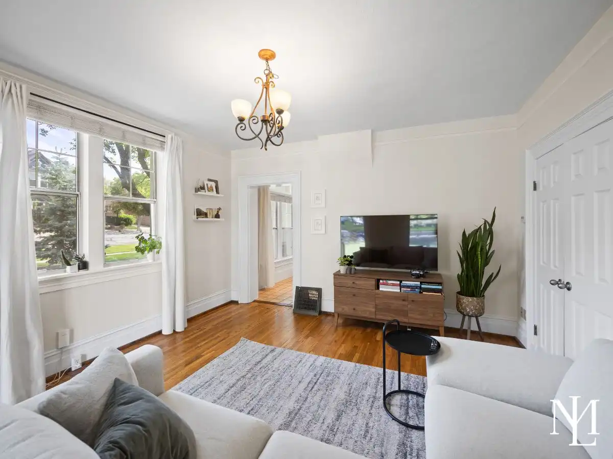 Bright living room featuring hardwood floors, large windows, white trim, and natural light