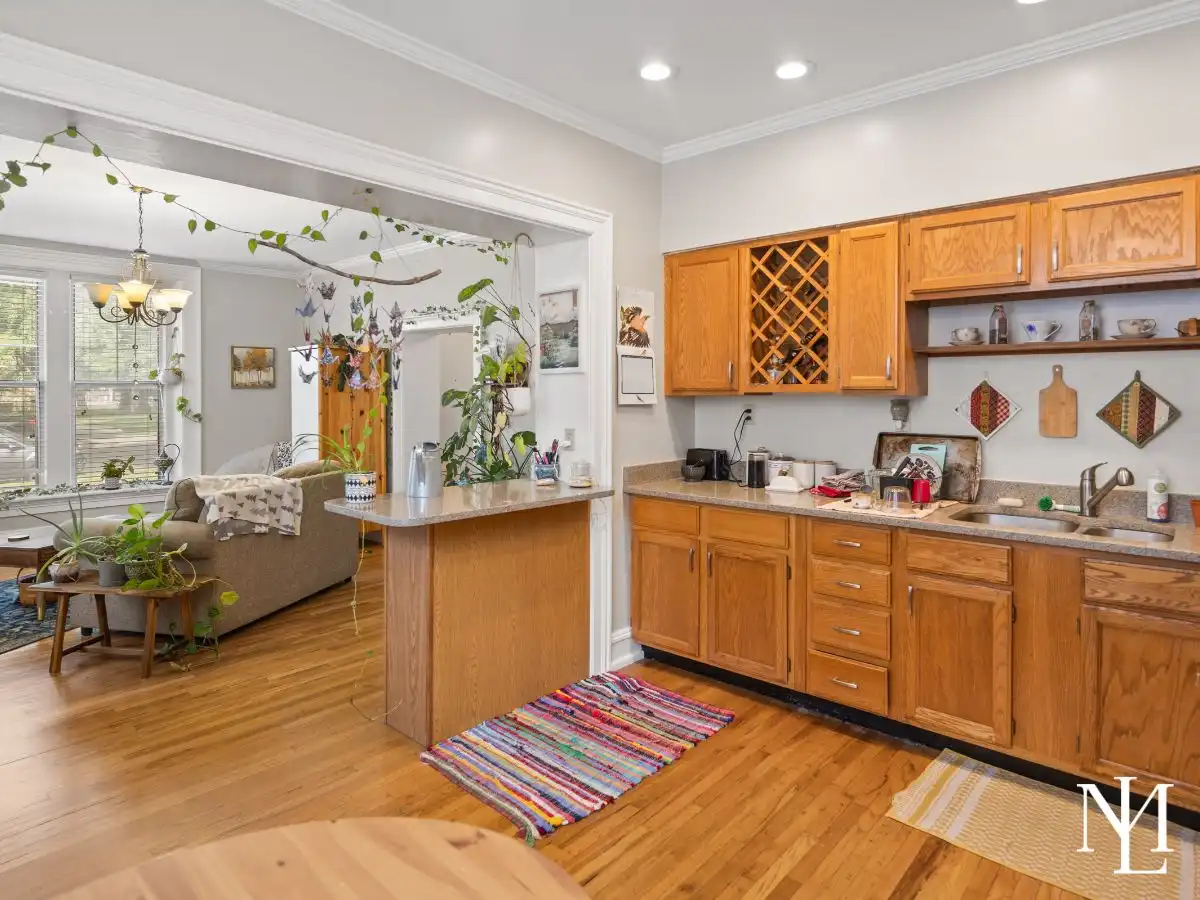 Kitchen with wood cabinetry, hardwood floors, open pass-through, and adjoining living space