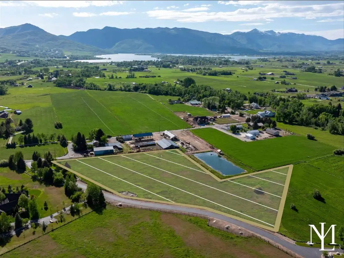 Aerial view of Huntsville, Utah land with outlined subdivided lots, private pond, and Pineview Reservoir in the distance.