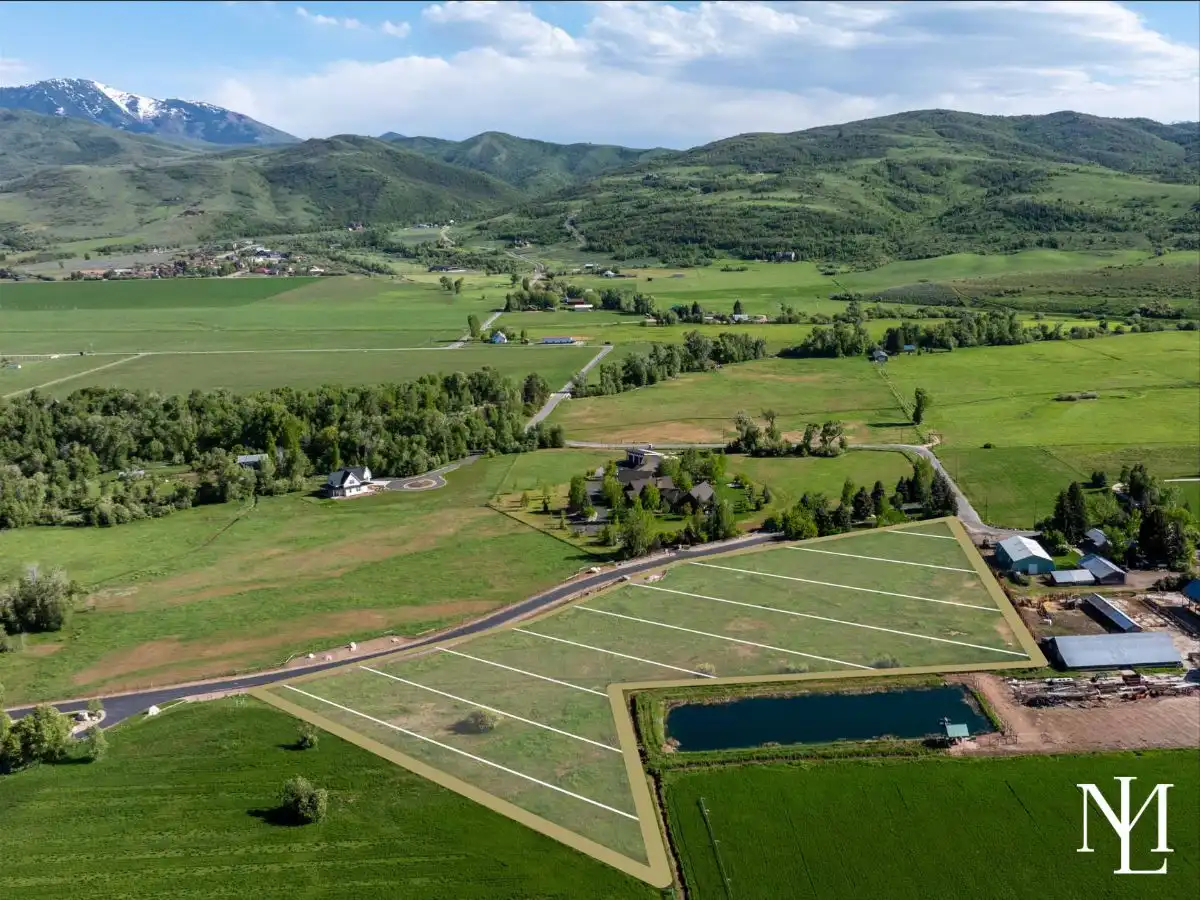 Drone photo of Ogden Valley parcel with lot lines marked, pond frontage, and sweeping views of surrounding green foothills.