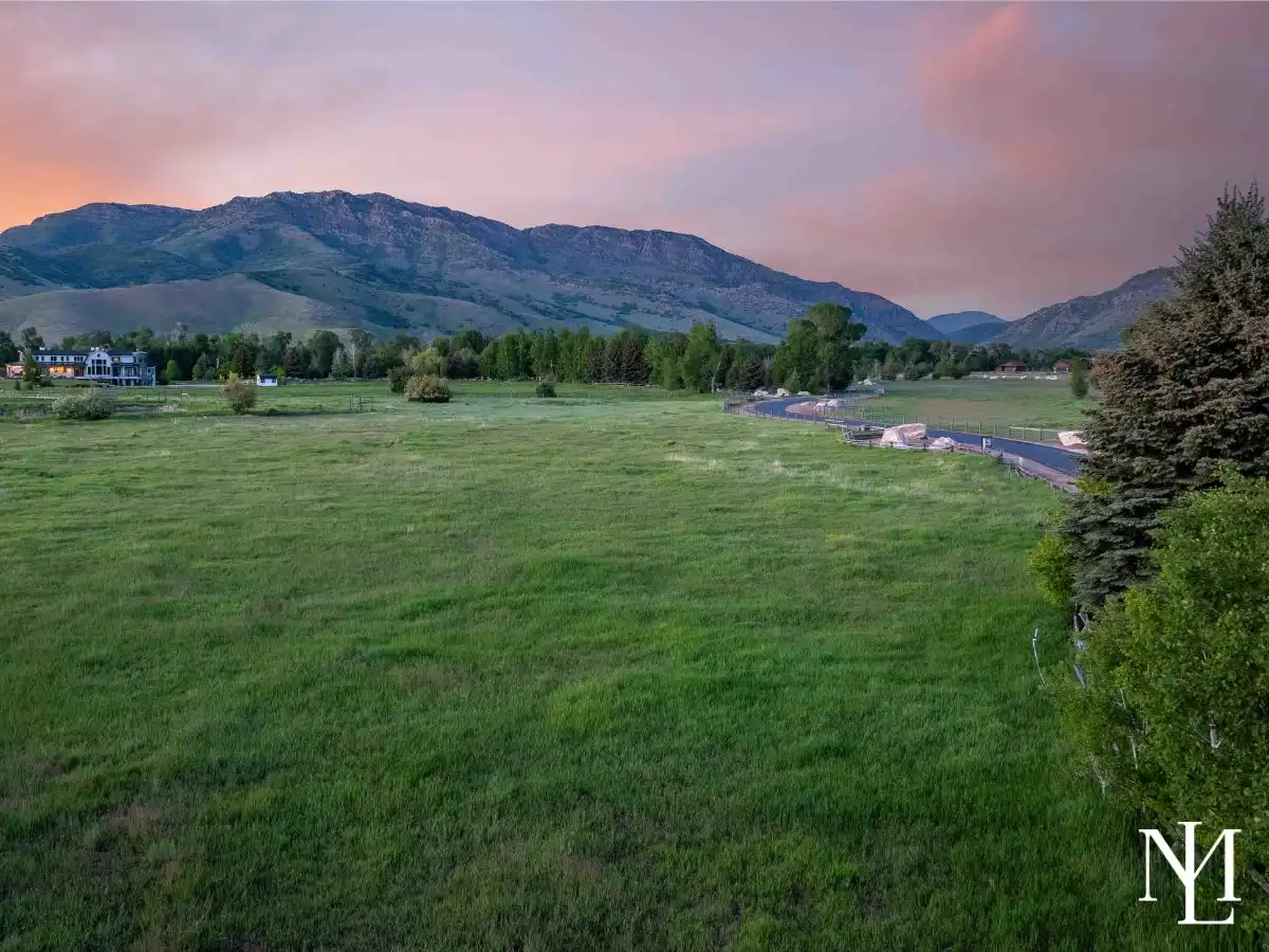 Evening view across open field and paved road toward mountain peaks, showing the quiet rural setting in Ogden Valley.