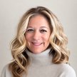 Colette McQuown smiling professional portrait for Mountain Luxury in a cream turtleneck against a neutral background