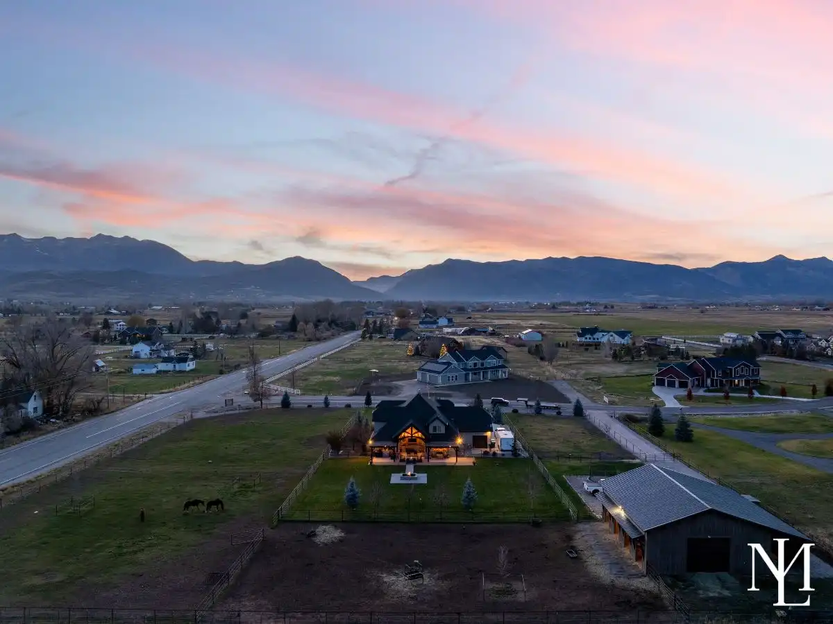 Aerial sunset view of an Ogden Valley horse property with fenced pasture, barn, and mountain backdrop near Huntsville, Utah.