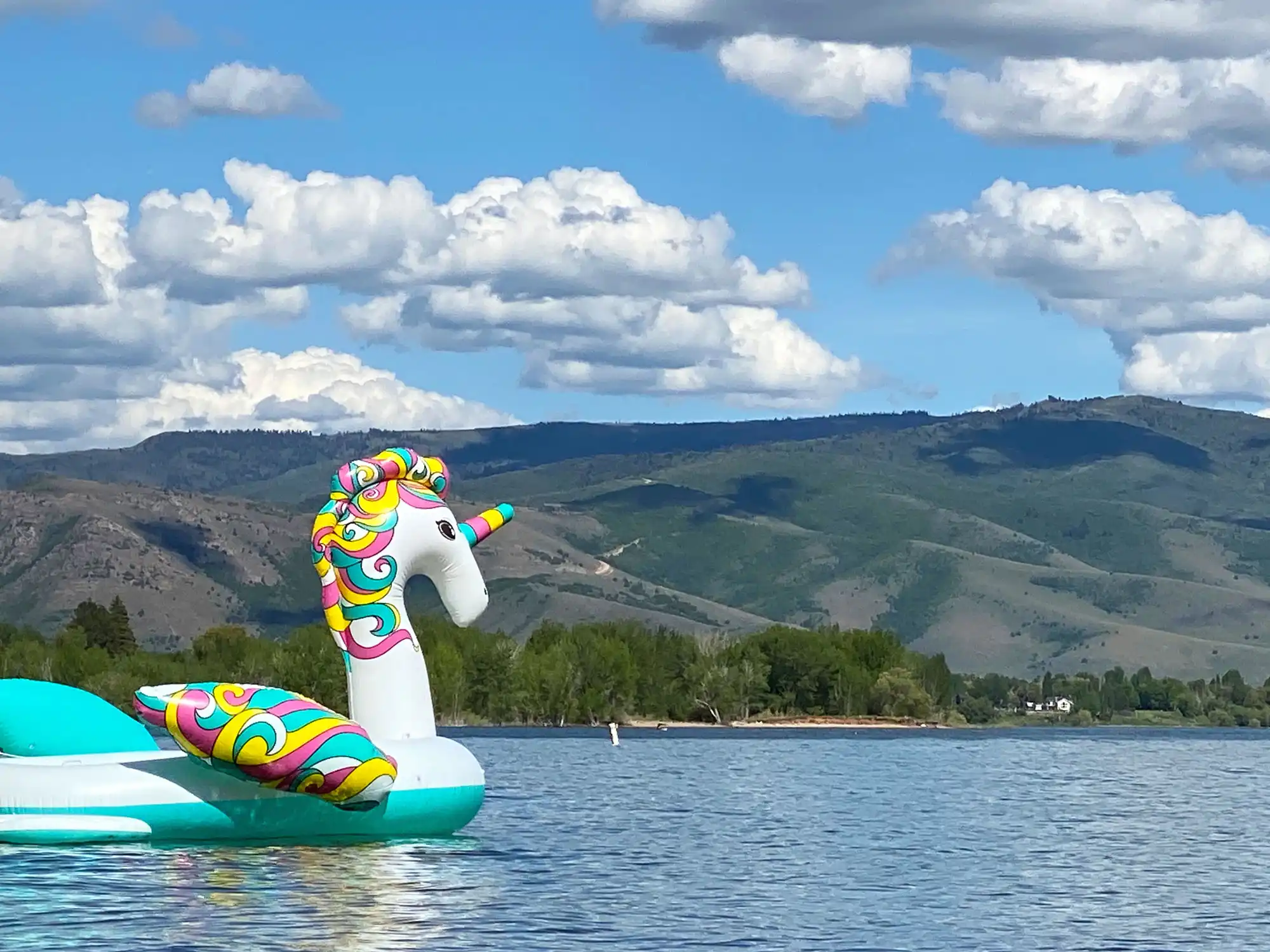 Colorful unicorn lake float on Pineview Reservoir in Ogden Valley, Utah with mountain views and summer recreation scene