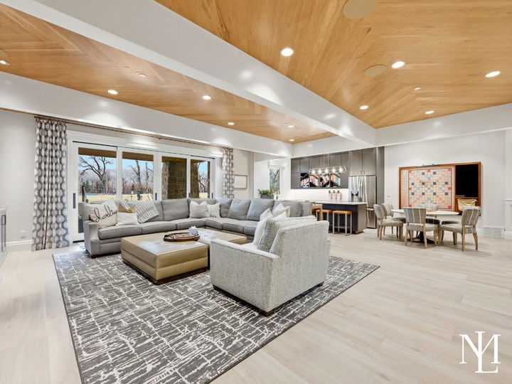 Expansive lower-level family room with sectional seating, game table, kitchenette, and sliding doors to outdoor patio.