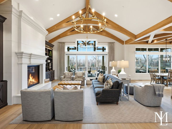 Vaulted great room with exposed timber trusses, statement chandelier, fireplace, and open layout in luxury Ogden Valley residence.