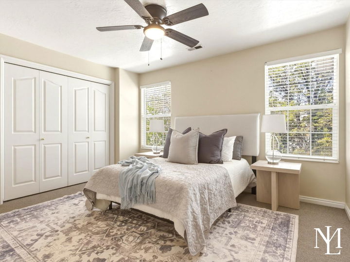 Primary bedroom in Draper townhome with large windows, ceiling fan, neutral carpet, and bright natural light