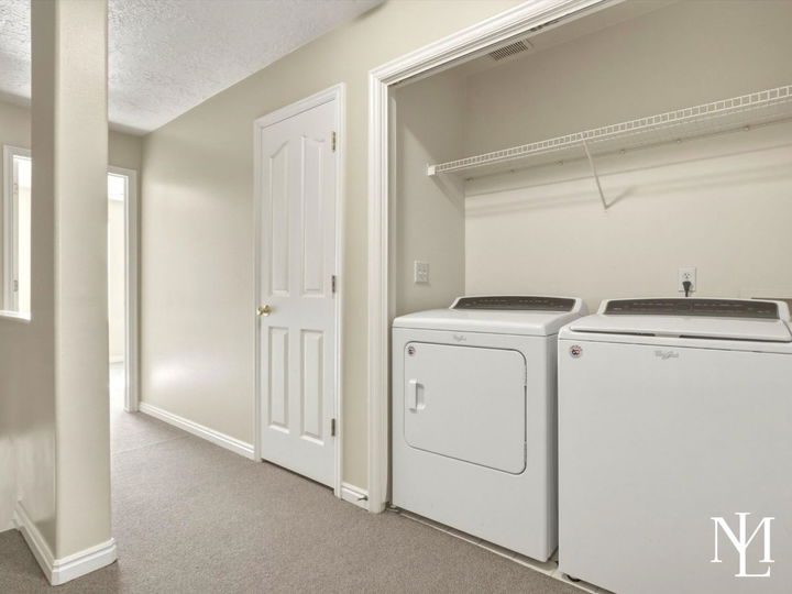 Laundry area in Draper townhome with washer and dryer, hallway access, and practical upper-level layout