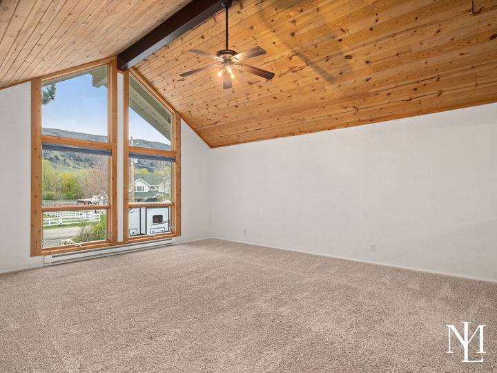 Vaulted living room with wood plank ceiling, large picture windows, and mountain views in Eden, Utah home.