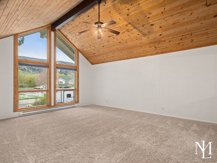 Vaulted living room with wood plank ceiling, large picture windows, and mountain views in Eden, Utah home.