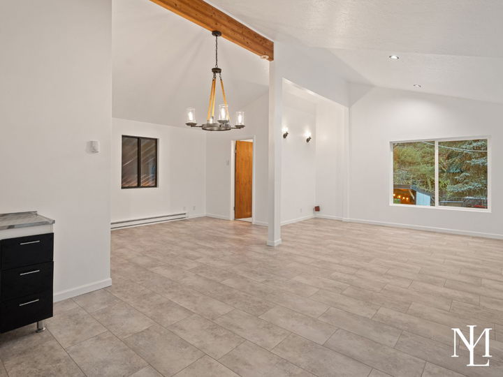 Spacious lower-level flex room with tile flooring, high ceilings, and open layout for recreation or gathering.