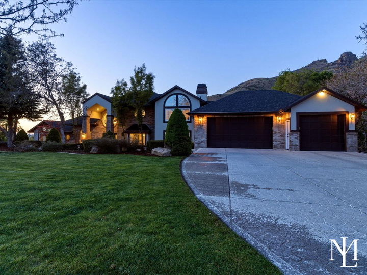 Twilight exterior of luxury home at 3311 Cove Cir in Layton, Utah with manicured lawn, mountain backdrop, and spacious 3-car garage.