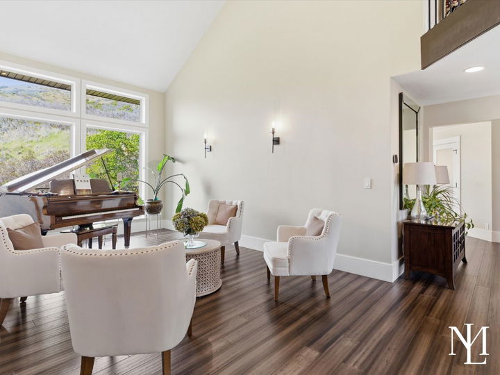 Bright sitting room with grand piano, soaring ceilings, and large windows inside luxury Layton Utah home.