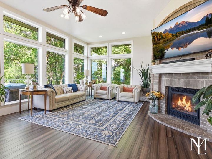 Sun-filled living room with fireplace, oversized windows, and wooded views in beautifully updated Layton Utah home.